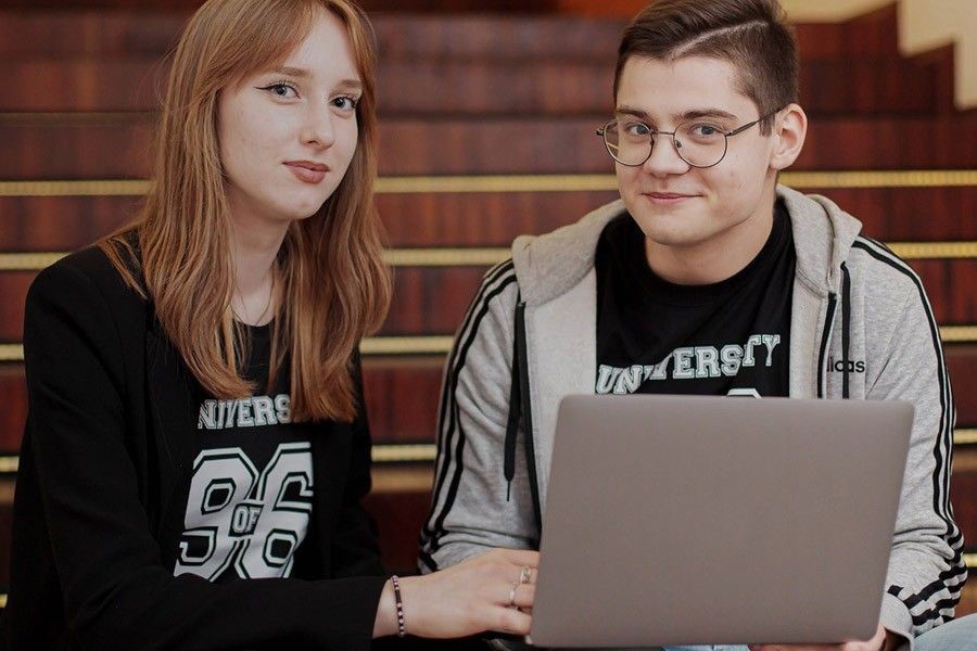 Dwoje studentów siedzi przed laptopem