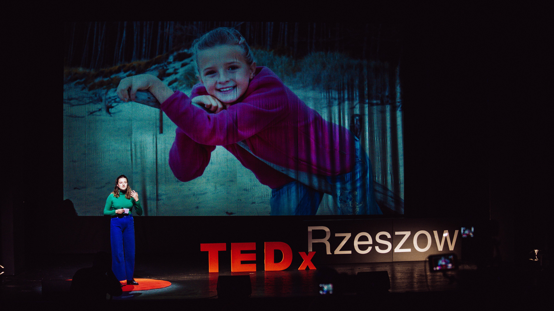 Prelegentka Dominika Lasota na tle swojego zdjęcia z dzieciństwa podczas wydarzenia TEDx Rzeszów Countdown WSIiZ