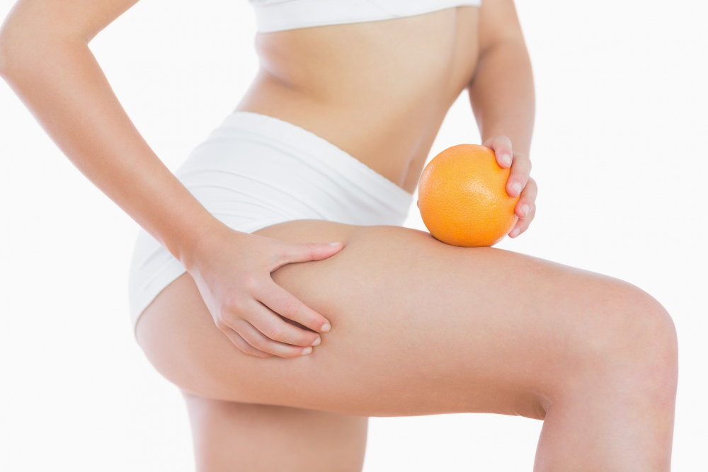 Zdjęcie kobiecego uda i pomarańczy w kontekście tematu - cellulitu
