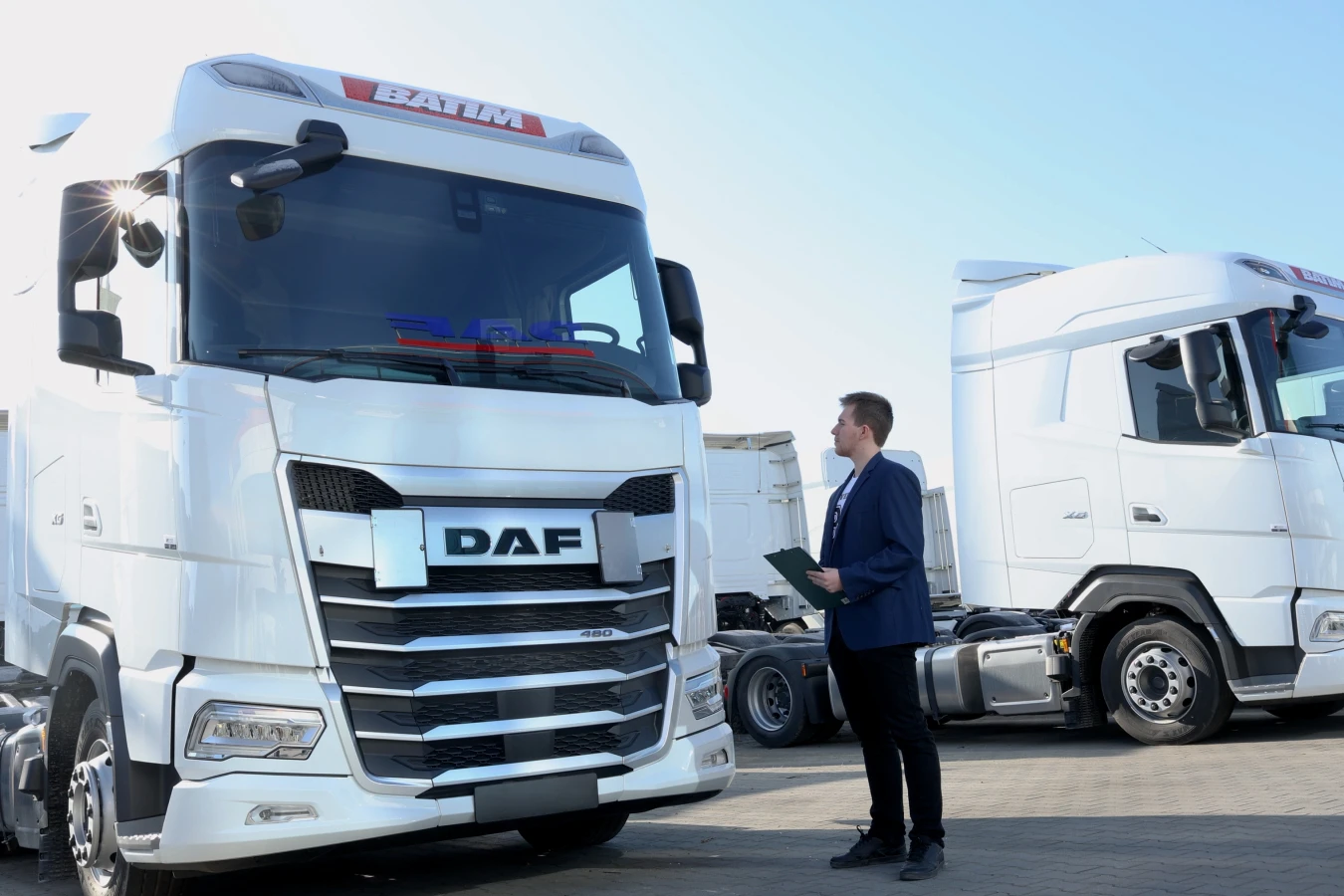 Student kierunku Transport, Spedycja i Obsługa Celna stoi przy samochodzie ciężarowym marki DAF