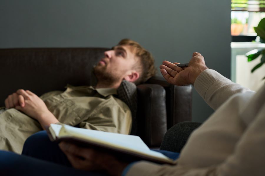 man-lying-down-while-talking-to-therapist